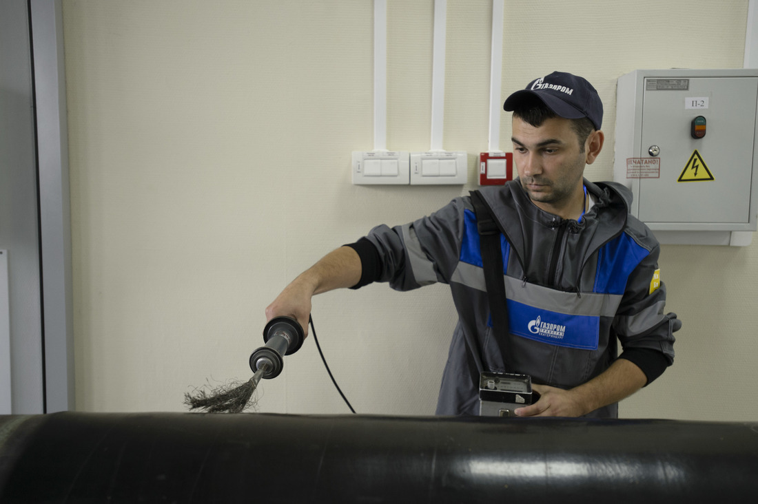 Специалист по защите подземных трубопроводов от коррозии проверяет диэлектрическую сплошность полимерного покрытия трубы